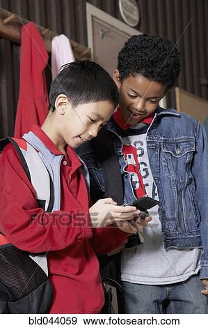 Stock Photo - Multi-ethnic school boys looking at cell phone. Fotosearch