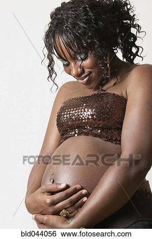 Stock Photograph - Pregnant African American woman hugging belly. Fotosearch