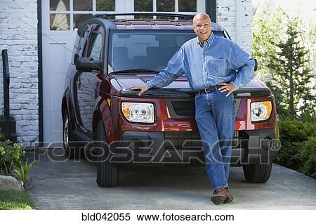 Stock Photography - Senior African American man leaning on car. Fotosearch