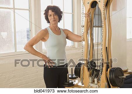 Senior woman standing next to exercise equipment View Large Photo Image Stock Image - Senior woman standing next to exercise equipment. Fotosearch