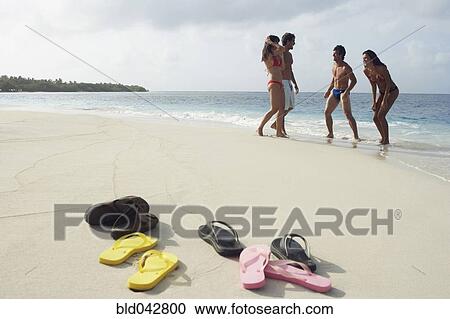Stock Image - Shoes on beach with people in background. Fotosearch
