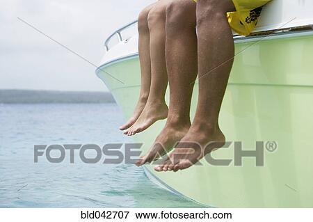 Stock Photo - South American couple dangling feet off of boat. Fotosearch