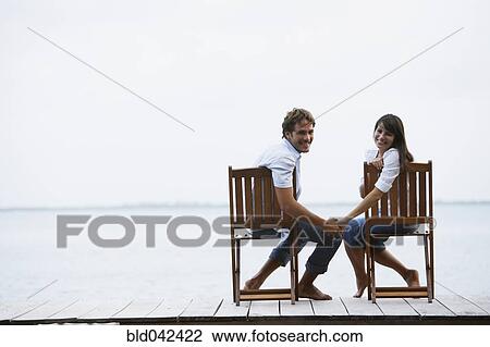 Stock Image - South American couple holding hands on dock. Fotosearch