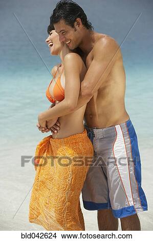 Picture - South American couple hugging at beach. Fotosearch