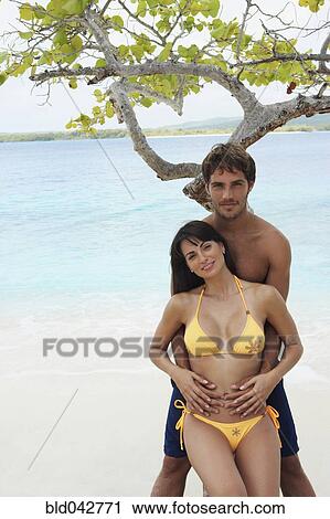 Stock Image - South American couple hugging at beach. Fotosearch