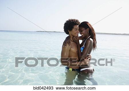 Stock Image - South American couple hugging in water. Fotosearch