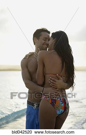 Stock Image - South American couple hugging on beach. Fotosearch