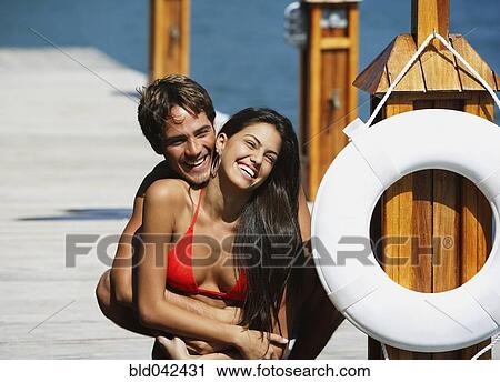 Stock Image - South American couple hugging on dock. Fotosearch