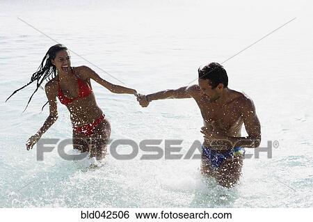 Stock Photograph - South American couple running in water. Fotosearch