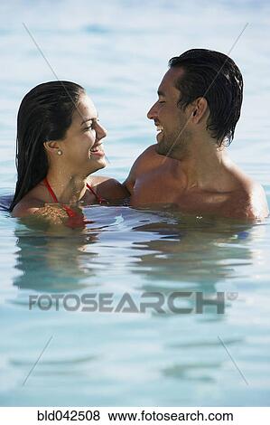 Stock Photo - South American couple smiling at each other in water. Fotosearch