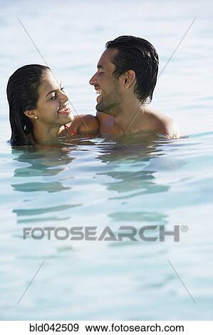 Stock Photo - South American couple smiling at each other in water. Fotosearch