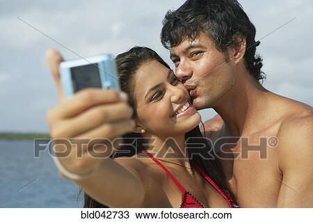 Stock Image - South American couple taking own photograph. Fotosearch