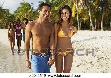Stock Photo - South American couple walking on beach. Fotosearch