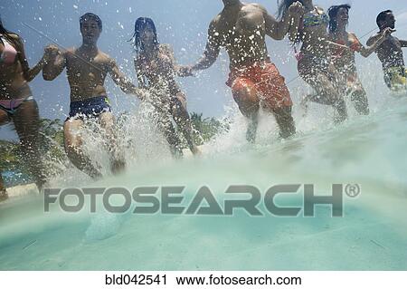 Stock Image - South American couples running in water. Fotosearch