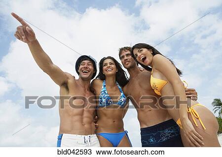 Stock Image - South American friends hugging at beach. Fotosearch