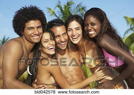 Stock Photo - South American friends hugging at beach. Fotosearch