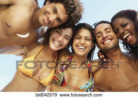 Stock Photo - South American friends hugging at beach. Fotosearch