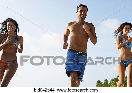 Picture - South American friends running at beach. Fotosearch