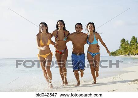 Stock Photo - South American friends running at beach. Fotosearch