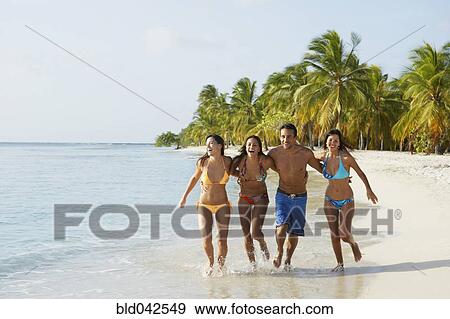 Stock Photo - South American friends running at beach. Fotosearch