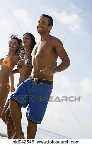 Stock Photograph - South American friends running at beach. Fotosearch