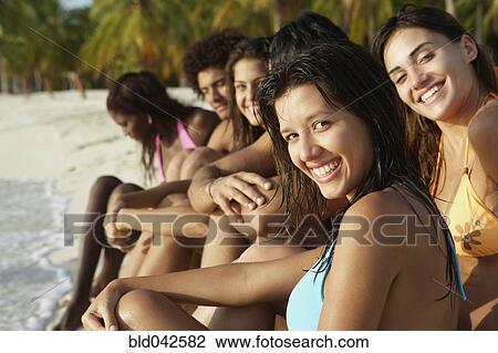 Stock Image - South American friends sitting on beach. Fotosearch