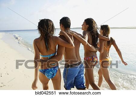 Stock Image - South American friends walking on beach. Fotosearch