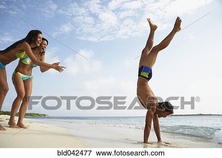 Stock Photo - South American man doing handstand on beach. Fotosearch