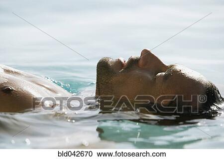 Stock Image - South American man floating in water. Fotosearch