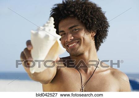 Stock Photo - South American man holding seashell. Fotosearch