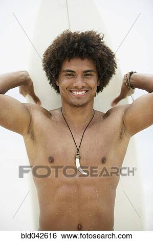Stock Photograph - South American man holding surfboard. Fotosearch