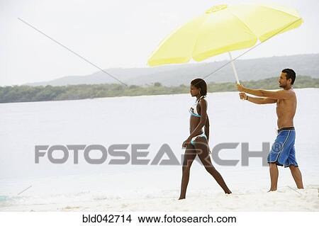 South American man holding umbrella for woman at beach View Large Photo Image Picture - South American man holding umbrella for woman at beach. Fotosearch