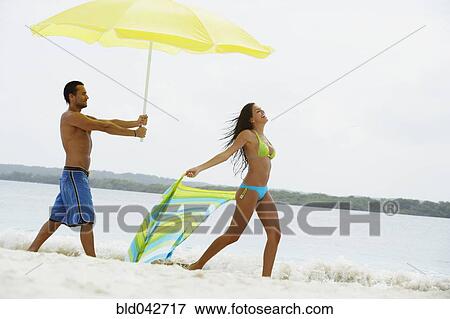 South American man holding umbrella for woman at beach View Large Photo Image Stock Photo - South American man holding umbrella for woman at beach. Fotosearch