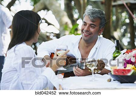 Stock Image - South American man playing guitar for wife. Fotosearch