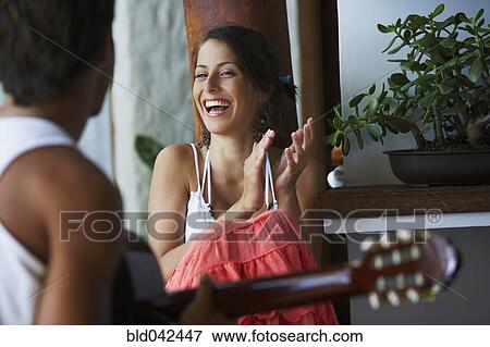 Stock Photo - South American man playing guitar for girlfriend. Fotosearch