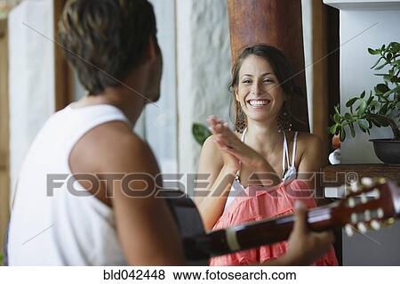 Stock Photo - South American man playing guitar for girlfriend. Fotosearch