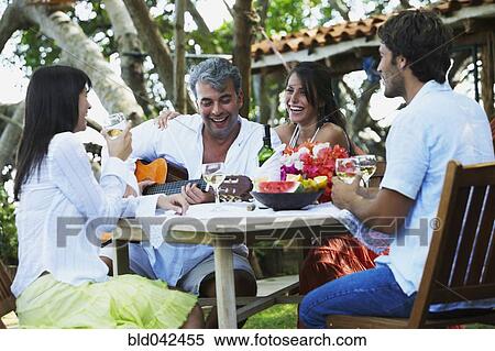 Stock Photography - South American man playing guitar for friends. Fotosearch