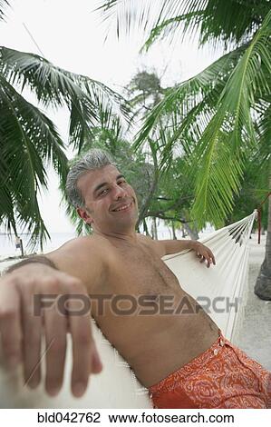Stock Image - South American man sitting in hammock. Fotosearch