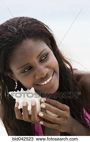 Stock Image - South American woman holding seashell. Fotosearch