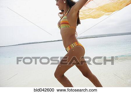 Stock Image - South American woman running on beach. Fotosearch
