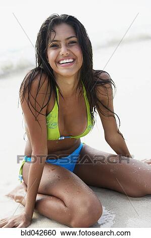 Stock Image - South American woman sitting on beach. Fotosearch