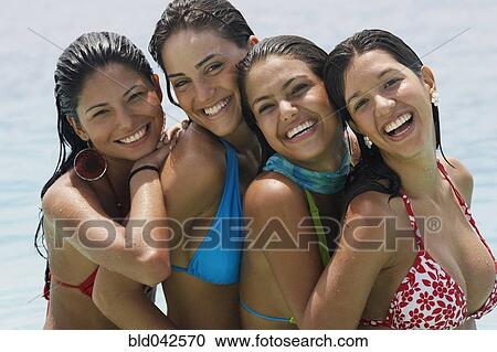 Stock Image - South American women hugging at beach. Fotosearch