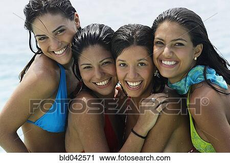 Stock Image - South American women hugging at beach. Fotosearch