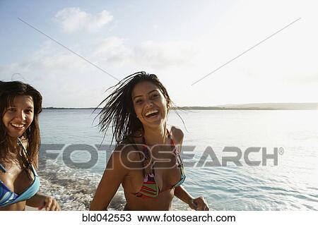 Stock Image - South American women running at beach. Fotosearch