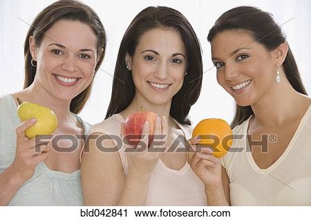 Three young women holding fruit View Large Photo Image Stock Image - Three young women holding fruit. Fotosearch