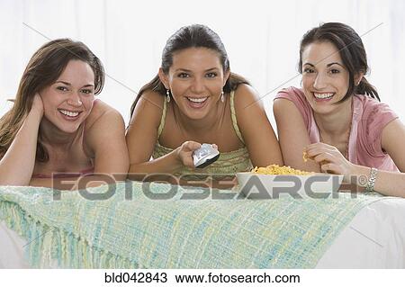 Three young women watching television View Large Photo Image Stock Image - Three young women watching television. Fotosearch