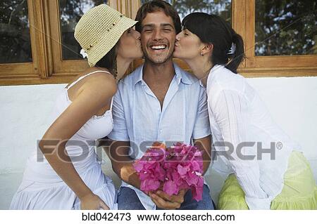 Two women kissing man on both cheeks View Large Photo Image Stock Image - Two women kissing man on both cheeks. Fotosearch