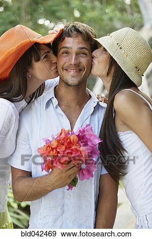Stock Photo - Two women kissing man on both cheeks. Fotosearch