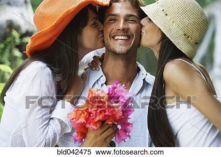 Stock Photography - Two women kissing man on both cheeks. Fotosearch