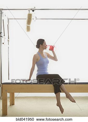 Woman drinking water on exercise equipment View Large Photo Image Stock Image - Woman drinking water on exercise equipment. Fotosearch